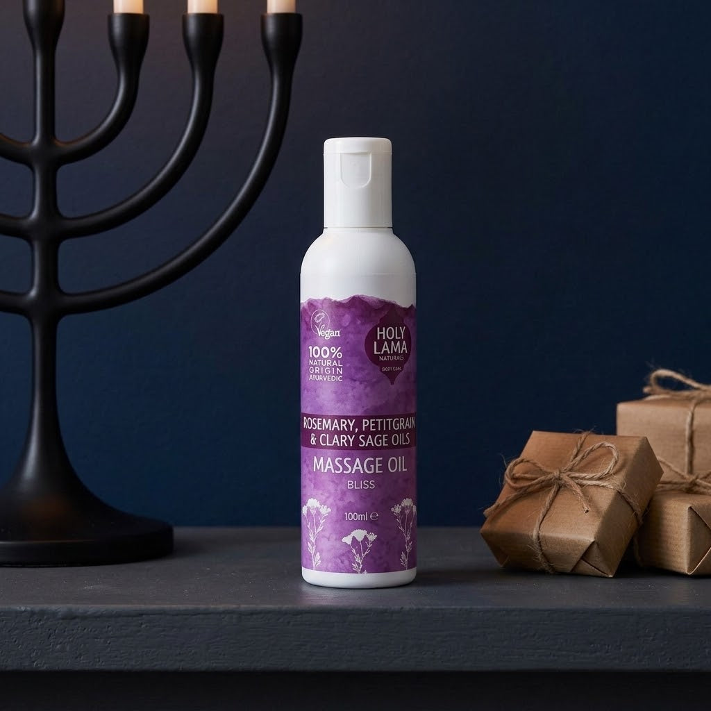flesje bliss massageolie op een donkere tafel met een kandelaar en kadootjes 