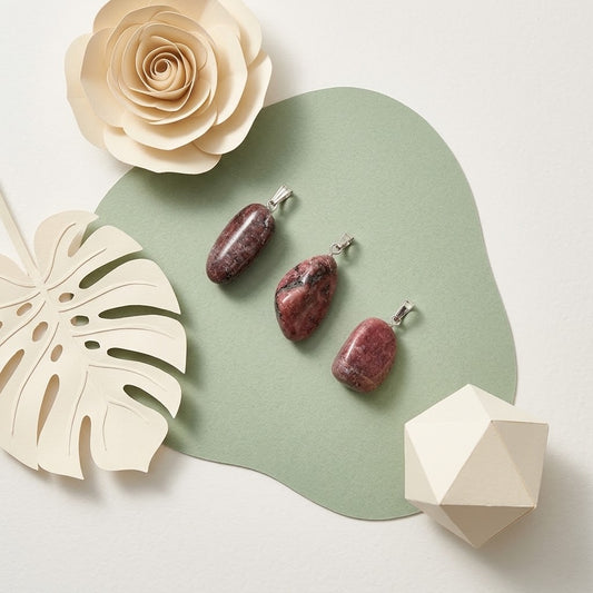 rhodoniet hangers op groene ondergrond met beige bloemknutsels