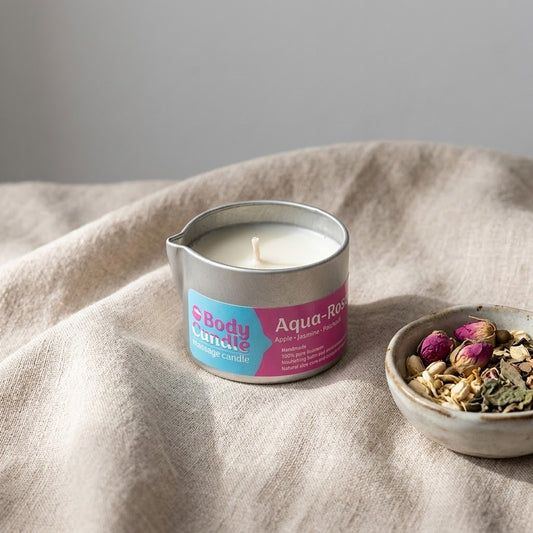 aqua rose massagekaars op een linnen doek met wat gedroogde bloemen