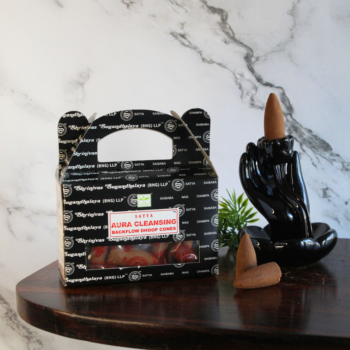 sfeerbeeld van een doosje backflow aura cleansing kegels met een marmeren achtergrond en een backflow brander met wat losse kegeltjes