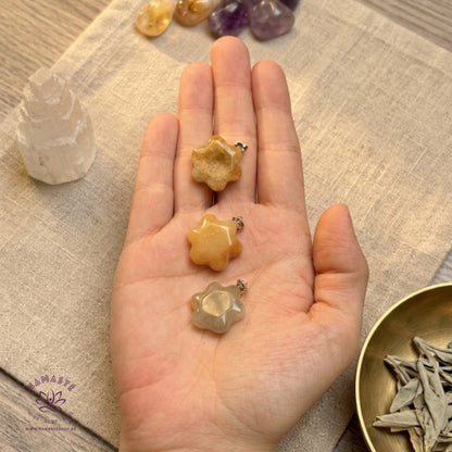 gele jade hangers op een hand met een linnen doek onder en seleniet, trommelstenen en gedroogde kruiden
