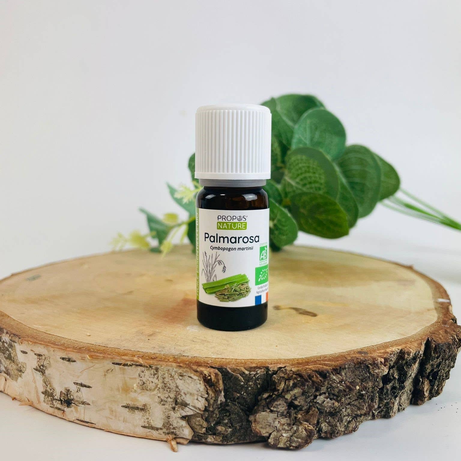 flesje palmarosa olie van propos' nature op een schijf hout