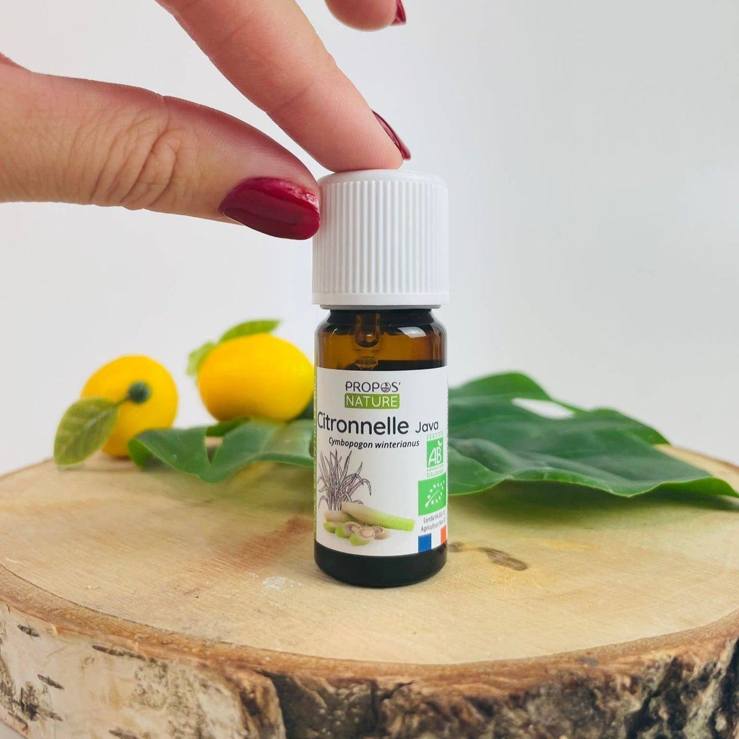 propos'nature citronella olie op een stuk hout aangeraakt door een vrouwenhand