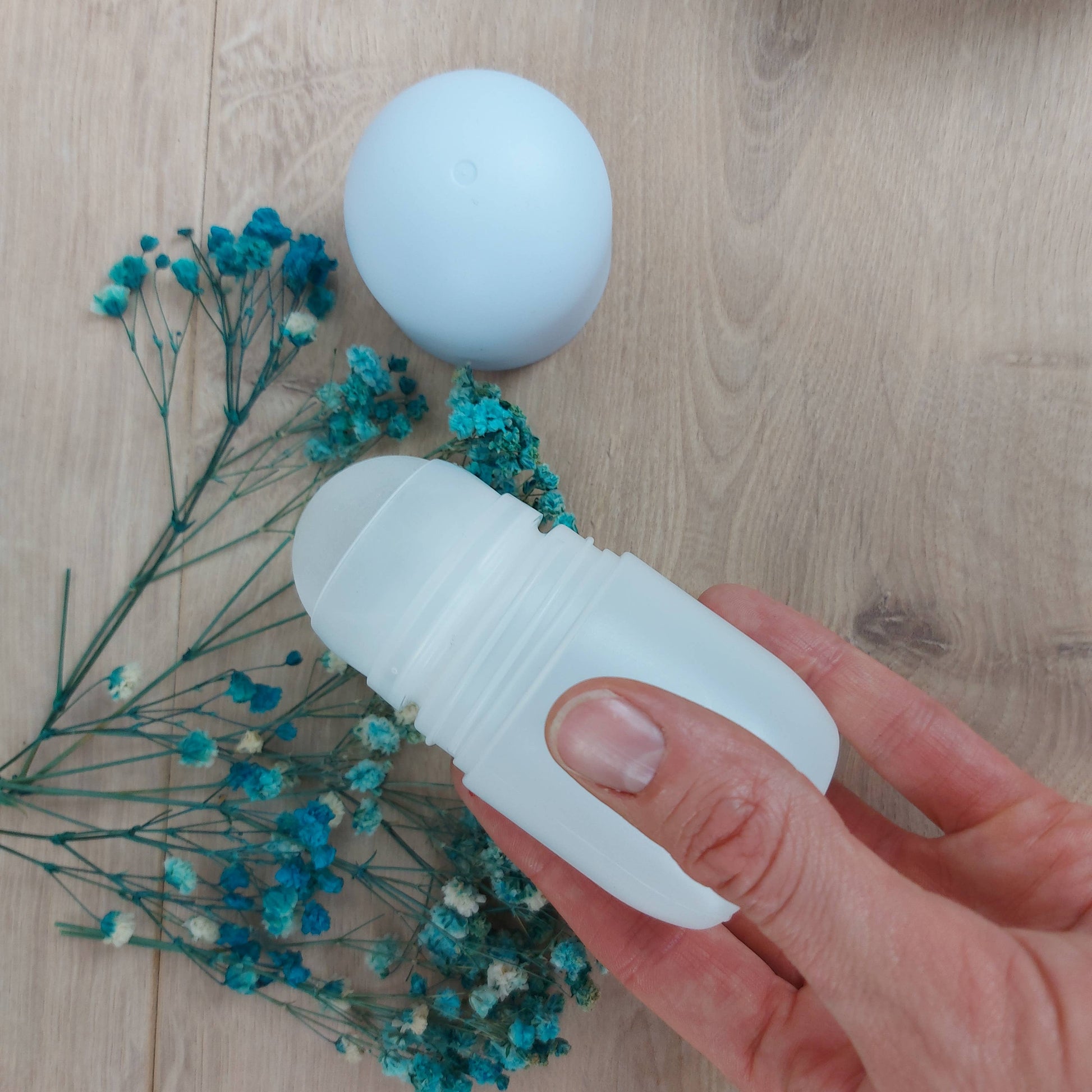 geopende rollerfles in de hand met gedroogde bloemen bij