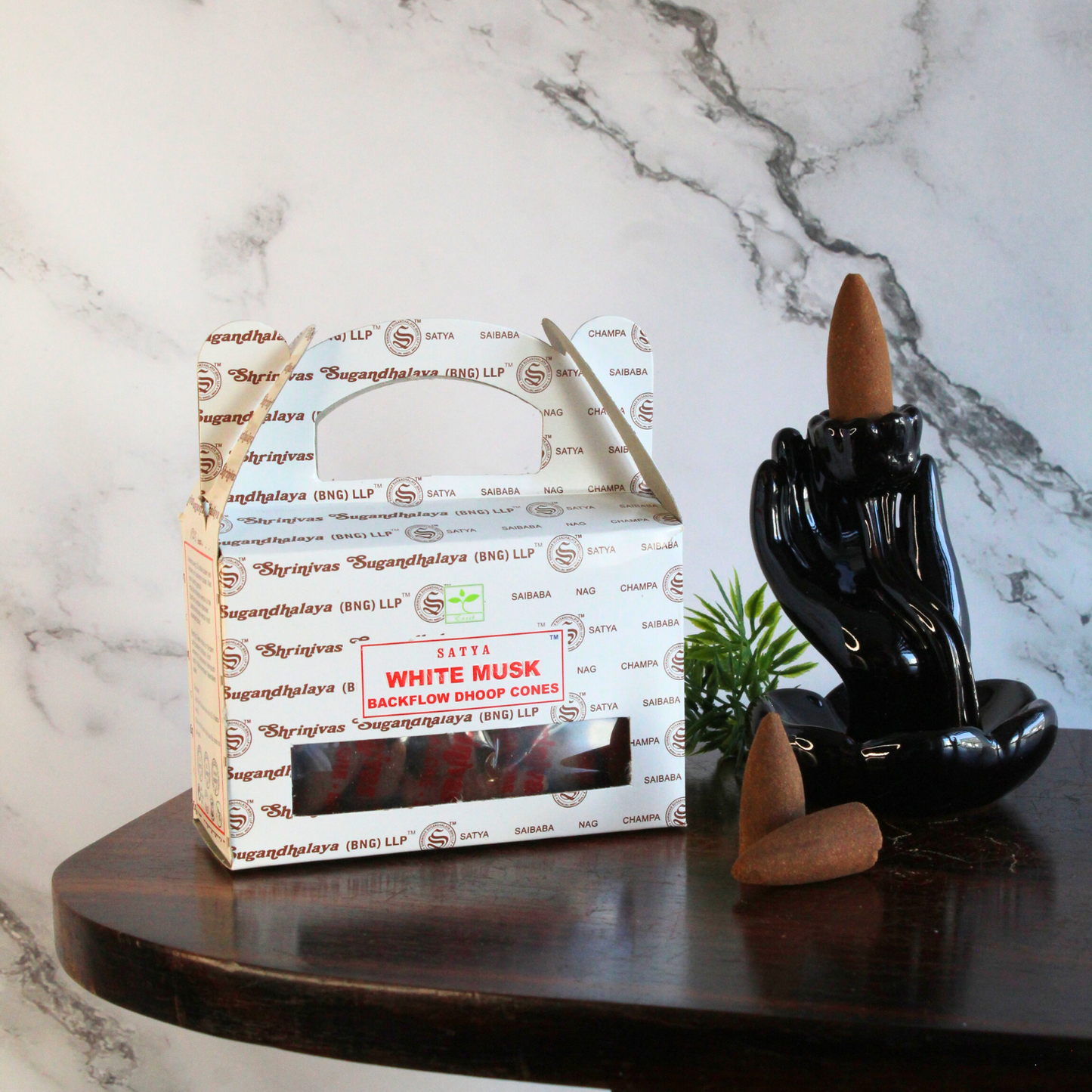 doosje en losse kegels van white musk backflow naast een brander op een houten tafeltje met marmeren achtergrond